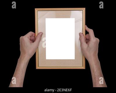 Ein Mann hängt einen hölzernen Fotorahmen an der Wand. Isoliert auf Schwarz Stockfoto