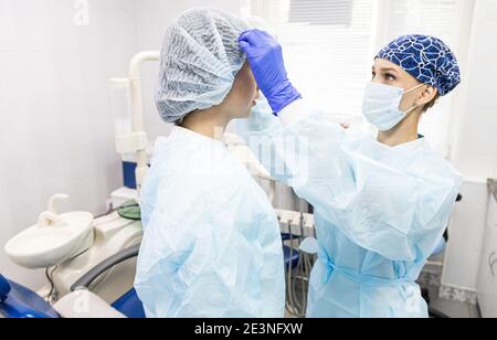 Zahnmedizin Konzept. Professionelle zahnärztliche Dienstleistungen und moderne Ausrüstung ohne Schmerzen. Der Assistent des Arztes bereitet den Patienten vor und kleidet ihn für den Stockfoto