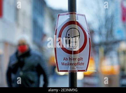 Solingen, Deutschland. Januar 2021. Ein Mann geht an einem Schild für die Maskenanforderung vorbei. Bundeskanzlerin Merkel und die Staats- und Regierungschefs haben sich darauf geeinigt, die Sperre bis Februar 14 zu verlängern. Quelle: Oliver Berg/dpa/Alamy Live News Stockfoto