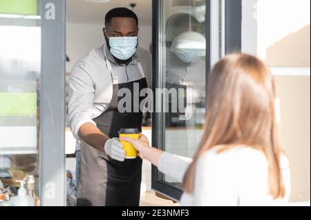 Ein afrikanischer Kellner in einer medizinischen Maske Stockfoto