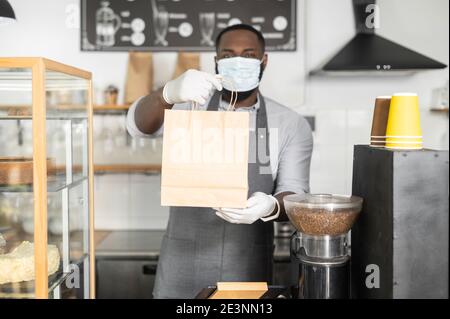 Ein afrikanischer Kellner in einer medizinischen Maske Stockfoto