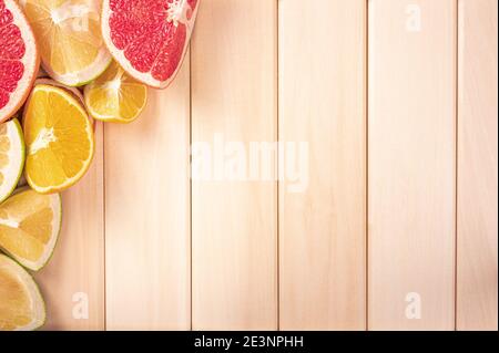 Schneiden von Zitrusfrüchten auf Holzhintergrund mit Kopierraum. Ecke von Holzbrettern Zitrusfrüchte. Orange, Limette, Zitrone, Orange in Scheiben geschnitten. Obst in der Co Stockfoto