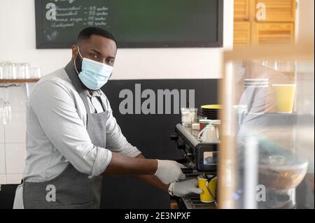 Ein afrikanischer Kellner in einer medizinischen Maske Stockfoto