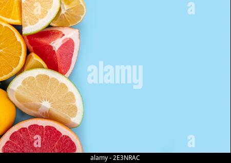 Flatlay Muster von Zitrusorange, Zitrone, Limette und Grapefruit Scheiben Hintergrund. Draufsicht. Minimalistisches Design. Rahmen von Zitrusfrüchten Lebensmittelmuster auf blauem Rückengro Stockfoto