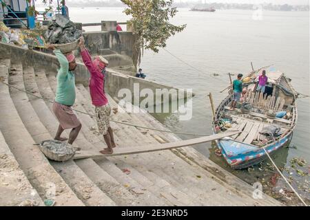 Der Schlick für die Götzenherstellung wird von einem Boot in Kumortuli Ghat entladen. Der ideale Schlamm für die Herstellung von Idolen ist Flussboden, der aus kolaghat genommen wird. Stockfoto