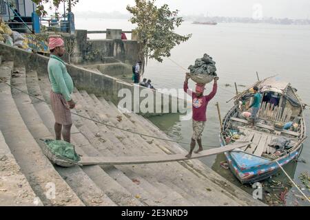 Der Schlick für die Götzenherstellung wird von einem Boot in Kumortuli Ghat entladen. Der ideale Schlamm für die Herstellung von Idolen ist Flussboden, der aus kolaghat genommen wird. Stockfoto