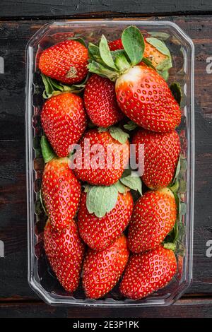 Transparentes Kunststofftablett, mit frisch gepflückten Erdbeeren, auf altem dunklen Holztischhintergrund, Draufsicht flach liegend Stockfoto