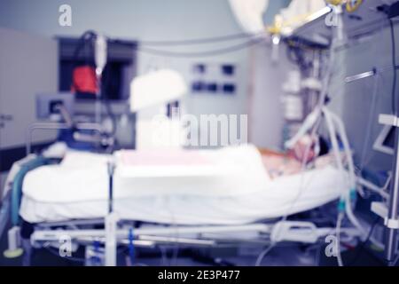 Männlicher Patient lyng im Bett auf der Intensivstation des Krankenhauses, unfokussierter Hintergrund. Stockfoto