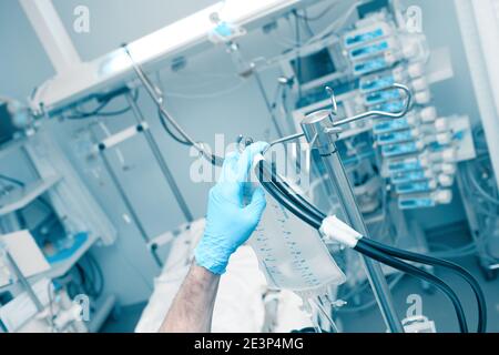 Der männliche Arzt stellt die medizinischen Geräte neben dem Patientenbett in der Intensivstation auf. Stockfoto