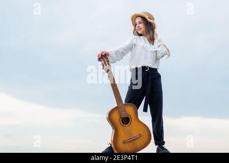 Voller Inspiration. Freiheit und Erfolg. Sänger. Happy teen Mädchen spielen Gitarre im Freien. Glückliche Kindheit. Hübsches Kind auf Himmel Hintergrund. Country-Musik-Konzept. Kid Fashion-Stil. Copy space. Stockfoto