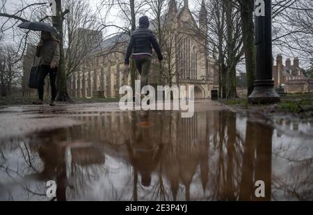 Die Menschen gehen durch das Gelände der Winchester Cathedral in Winchester, Hampshire, während Storm Christoph weite Überschwemmungen, Stürme und Schnee in Teile Großbritanniens bringen wird. Es wird erwartet, dass es in Großbritannien zu heftigen Regenfällen kommt, wobei das Met Office warnt, dass Häuser und Unternehmen überschwemmt werden und Schäden an einigen Gebäuden verursachen. Bilddatum: Mittwoch, 20. Januar 2021. Stockfoto