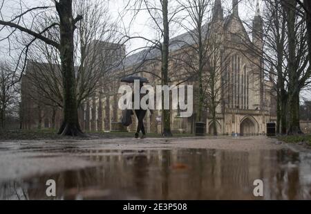 Eine Person geht durch das Gelände der Winchester Cathedral in Winchester, Hampshire, während Storm Christoph weite Überschwemmungen, Stürme und Schnee in Teile Großbritanniens bringen wird. Es wird erwartet, dass es in Großbritannien zu heftigen Regenfällen kommt, wobei das Met Office warnt, dass Häuser und Unternehmen überschwemmt werden und Schäden an einigen Gebäuden verursachen. Bilddatum: Mittwoch, 20. Januar 2021. Stockfoto