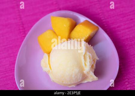 Kugel Mango-Eis von oben mit frischer Mango Stücke auf einem Teller Stockfoto