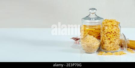 Banner mit verschiedenen Arten und Formen der trockenen italienischen Pasta. Rohe Pasta-Komposition auf weißem Tisch. Italienische Küche. Penne, Fusilli und Makkaroni Stockfoto