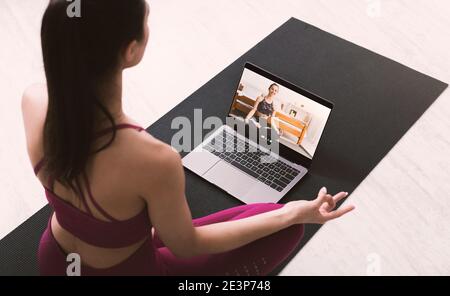 Junge Frau meditiert oder macht Yoga, nach Online-Video-Anweisungen von Personal Trainer, oben sehen Stockfoto