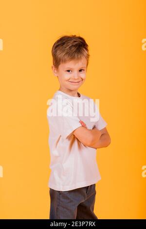 Portrait von glücklichen kleinen Jungen auf gelbem Hintergrund im Studio Stockfoto