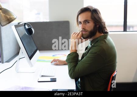 Porträt eines kaukasischen Mannes, der im kreativen Büro am Schreibtisch sitzt Stockfoto