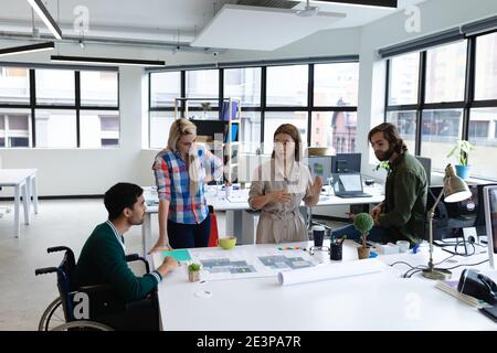 Eine vielfältige Gruppe von Geschäftskollegen, die sich die Entwürfe angeschaut und diskutiert haben Am Tisch Stockfoto