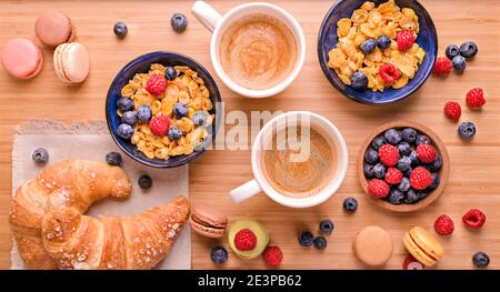 Aromatischer Kaffee, Müsli und süßes Gebäck für ein romantisches Frühstück. Gesundes Essen mit Beeren und Cappuccino für den Morgen. Oben. Hochwertige Fotos Stockfoto