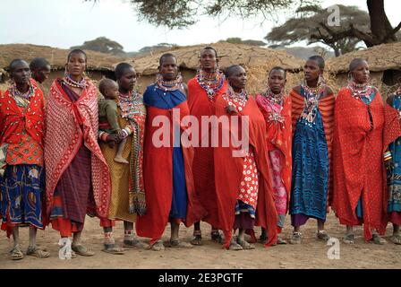 Masai Mara, Kenia - 23. August 2010: Gruppe nicht identifizierter afrikanischer Frauen aus dem Stamm der Masai in bunten Baumwollkleidern und Perlen Schmuck in einem Block Stockfoto