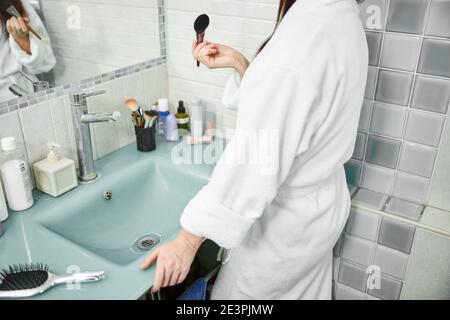Frau tut Mann am Morgen im Badezimmer Stockfoto