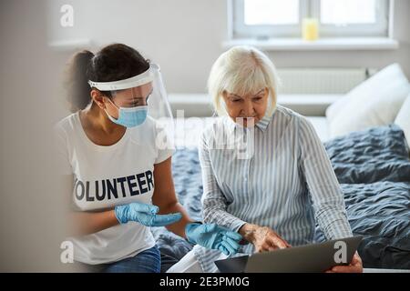 Pflegekraft Unterrichten eines Rentners der Arbeit mit Laptop Stockfoto