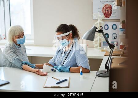 Medizinisches Personal, das während einer Blutdruckuntersuchung einen Monitor bediente Stockfoto