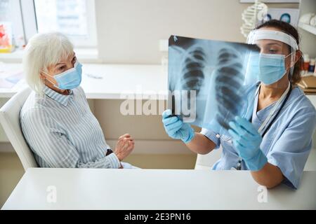 Ärztin, die ein Röntgendiagramm mit dem Patienten studiert Stockfoto