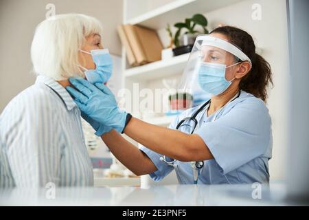 Arzt auf der Suche nach Nackenproblemen bei einem Patienten Stockfoto