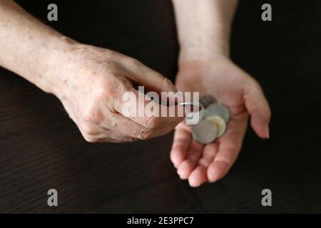 Ältere Frau zählt eine Münze, faltige weibliche Hände mit Metallgeld Nahaufnahme. Konzept der Armut, Rentenzahlungen, Rentner Stockfoto