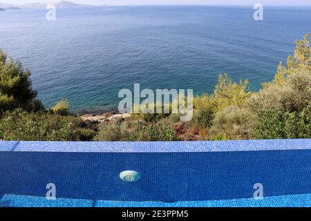 Swimmingpool umgeben von Bäumen auf blauem Meer und Bucht Hintergrund. Strand entspannen und Urlaub, genießen Sie das Lebenskonzept Stockfoto