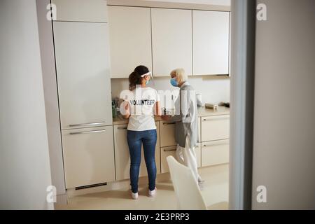 Rentner und ein Freiwilliger stehen an der Küchenarbeitspe Stockfoto