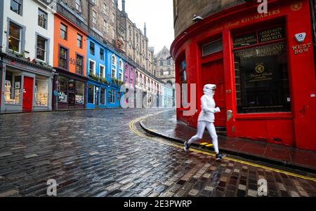 Edinburgh, Schottland, Großbritannien. 20. Januar 2021. Blick auf ruhige Straßen im Stadtzentrum von Edinburgh am Tag, nachdem der erste Minister Nicola Sturgeon angekündigt hatte, dass die nationale Sperre bis Februar verlängert werden würde. Die Straßen sind sehr ruhig und es gibt keine Geschäfte, die nicht unbedingt notwendig sind. Bild: Ein einjähriger Jogger läuft auf einer leeren Victoria Street in der Altstadt. Iain Masterton/Alamy Live News Stockfoto