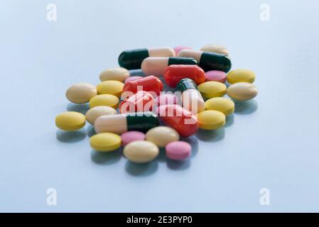 Bunte Pillen und Kapseln isoliert auf einem blauen Hintergrund. Medizinische Gesundheit oder Drogenabhängigkeit Konzept. Kopieren Sie Platz für Ihren Text. Stockfoto