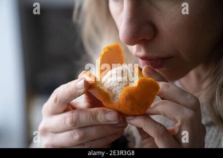 Kranke Frau, die versucht, den Geruch von frischer Mandarine-Orange zu spüren, hat Symptome von Covid-19, Corona-Virus Stockfoto