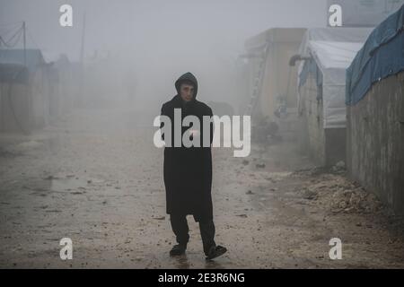 Barischa, Syrien. Januar 2021. Ein syrischer junger Mann steht auf einem schlammigen Durchgang in einem Lager für Binnenvertriebene, in der Nähe des Dorfes Barisha. Die Flüchtlingslager im Norden des Gouvernements Idlib sind von extremem Winterwetter mit Starkregen und Schneefall bedroht. Quelle: Anas Alkharboutli/dpa/Alamy Live News Stockfoto