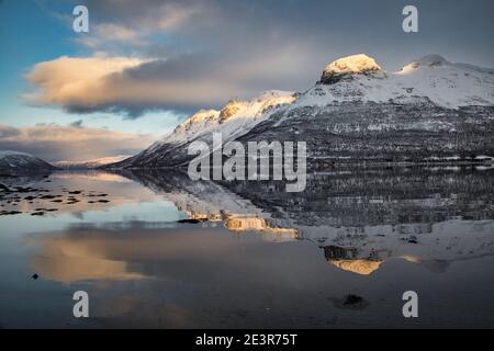 Norwegischer Berg spiegelt sich im Winterfjord Stockfoto