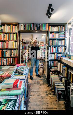 GREAT BRITAN / London / Buchhandlungen / der Inhaber Johnny de Falbe von John Sandoe Books in London. Der Buchhändler hält einen Stapel Bücher. Stockfoto