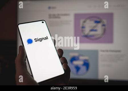 Mann hält ein Smartphone mit Signal Wessenger Zeichen und Logo Wird auf dem Bildschirm vor dem Signalnetz angezeigt Version Stockfoto