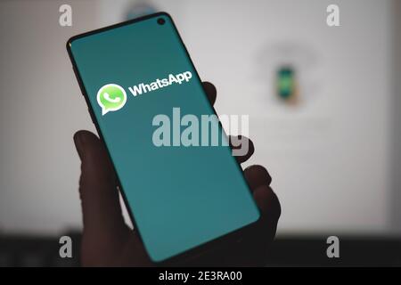 Mann, der ein Smartphone mit dem angezeigten Whatsapp Messenger App-Logo hält Auf dem Bildschirm vor der Whatsapp Web-Version Stockfoto