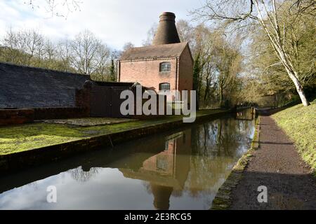 Ziegelbrennöfen im Coalport china Museum, Telford, Shropshire an einem Kanal mit Reflexionen im Wasser an einem schönen sonnigen Wintertag Stockfoto