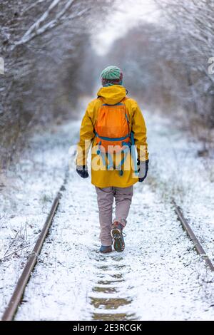 Rückansicht des Mannes, der einen Spaziergang durch den Wald genießt Im Winter Stockfoto