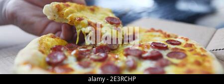 Mann nimmt Pizzablecken mit Wurst Nahaufnahme Stockfoto