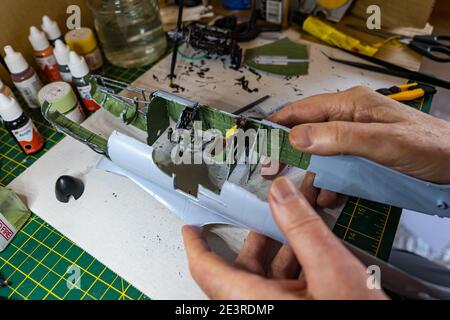 Mann, der Motor des Airfix Spitfire-Modellflugzeugs 1/24 Zoll Waage auf dem Schreibtisch Stockfoto