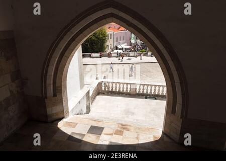 Sintra, Portugal - 14. August 2017: Steinbogen in der Mauer des Palacio Nacional de Sintra oder des Palastes von Sintra gehen gewöhnliche Menschen die Straße entlang Stockfoto