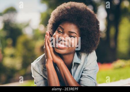 Nahaufnahme Foto Porträt von schwarz häutigen jungen Studentin lächeln Achtlos die Hände in der Nähe der im Park liegenden Wangenknochen halten Stockfoto
