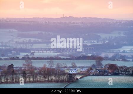 Die aufgehende Sonne verleiht der Landschaft südlich von Almscliffe Crag in Lower Wharfedale an einem bitterkalten Wintermorgen ein orangefarbenes Leuchten. Stockfoto