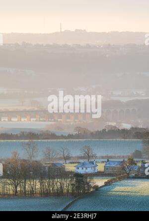 Der Blick südlich von Almscliffe Crag an einem bitterkalten Wintermorgen mit der aufgehenden Sonne, die neblige Schichten erzeugt, während die frostige Landschaft erwärmt. Stockfoto