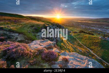 Eine Lücke in den Wolken ermöglicht es der untergehenden Sonne, die Sommerlandschaft rund um Ilkley Crags in glühendes goldenes Licht zu baden. Stockfoto