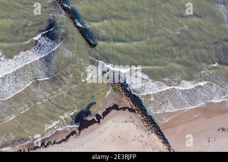 Luftaufnahme von oben nach unten von Wellen, die gegen alten Stein brechen Wellenbrecher Pier im Meer Stockfoto